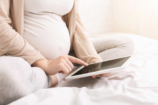 pregnant-woman-reading-maternity-blog-on-tablet-9XR5SJL